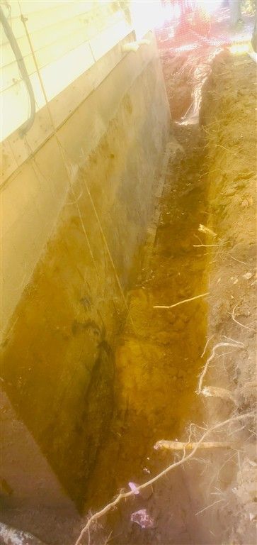 A trench-like structure with an angled concrete wall, possibly a construction site.