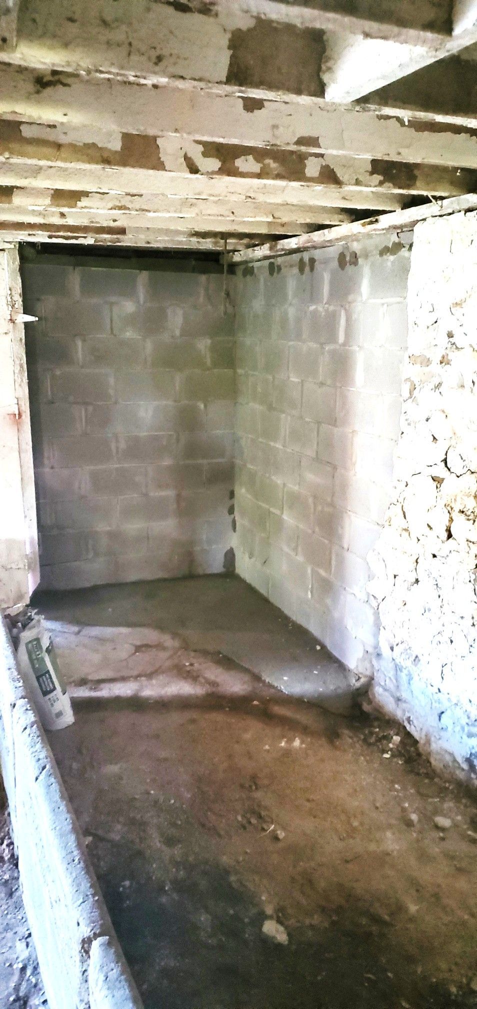 Interior of a dilapidated cinder block structure with a concrete floor. 