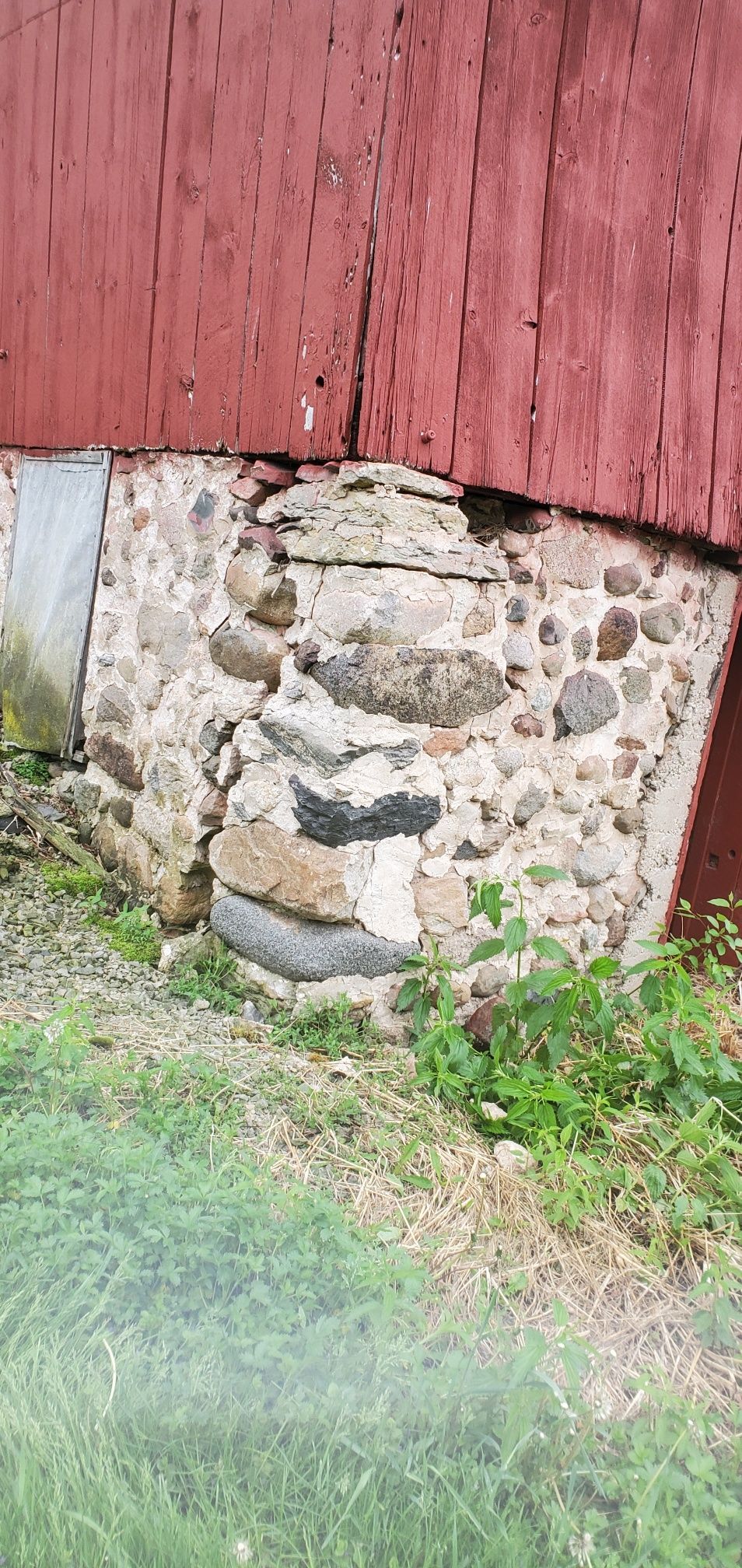 Stone foundation beneath a red wooden wall. 