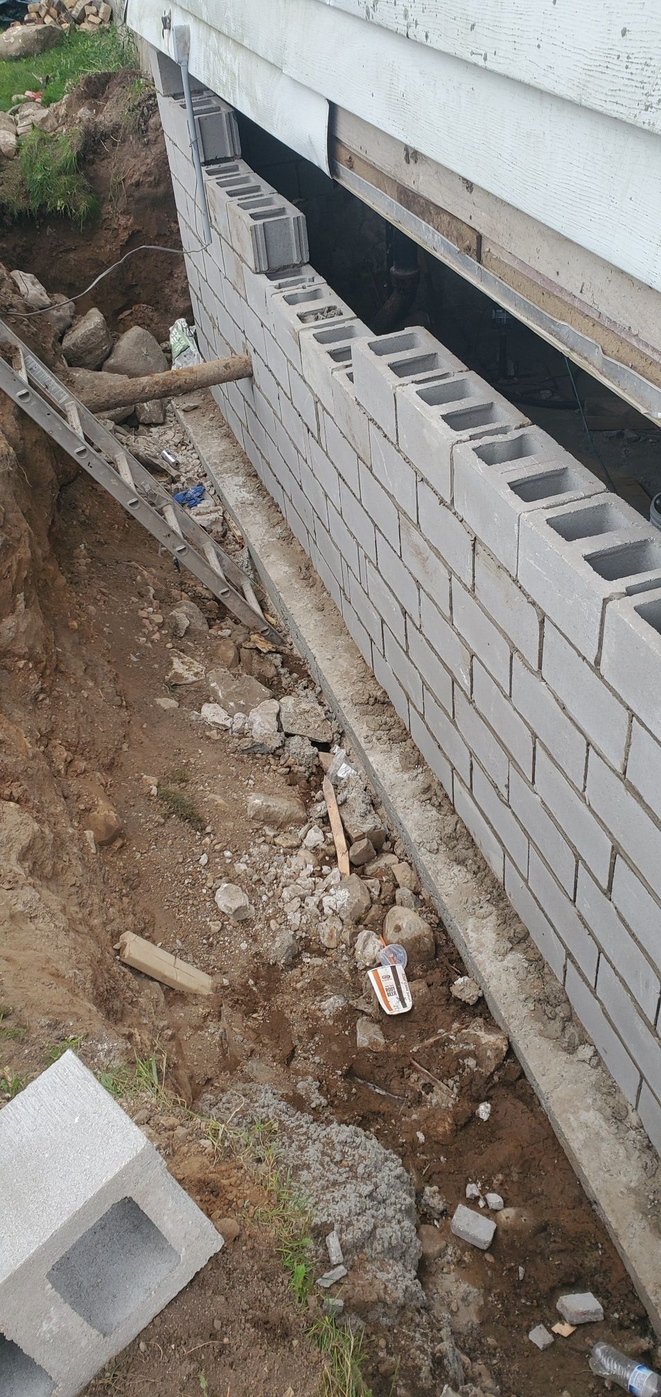 Construction of a cinder block wall along a building's foundation. 