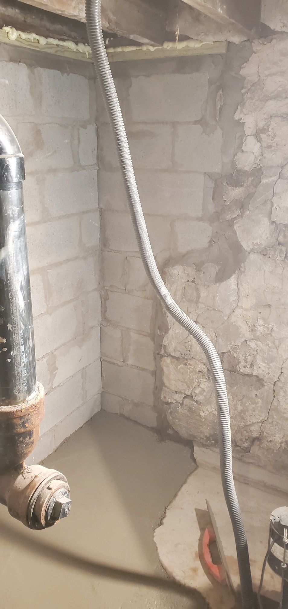 Basement corner with cinder block and stone walls. 
