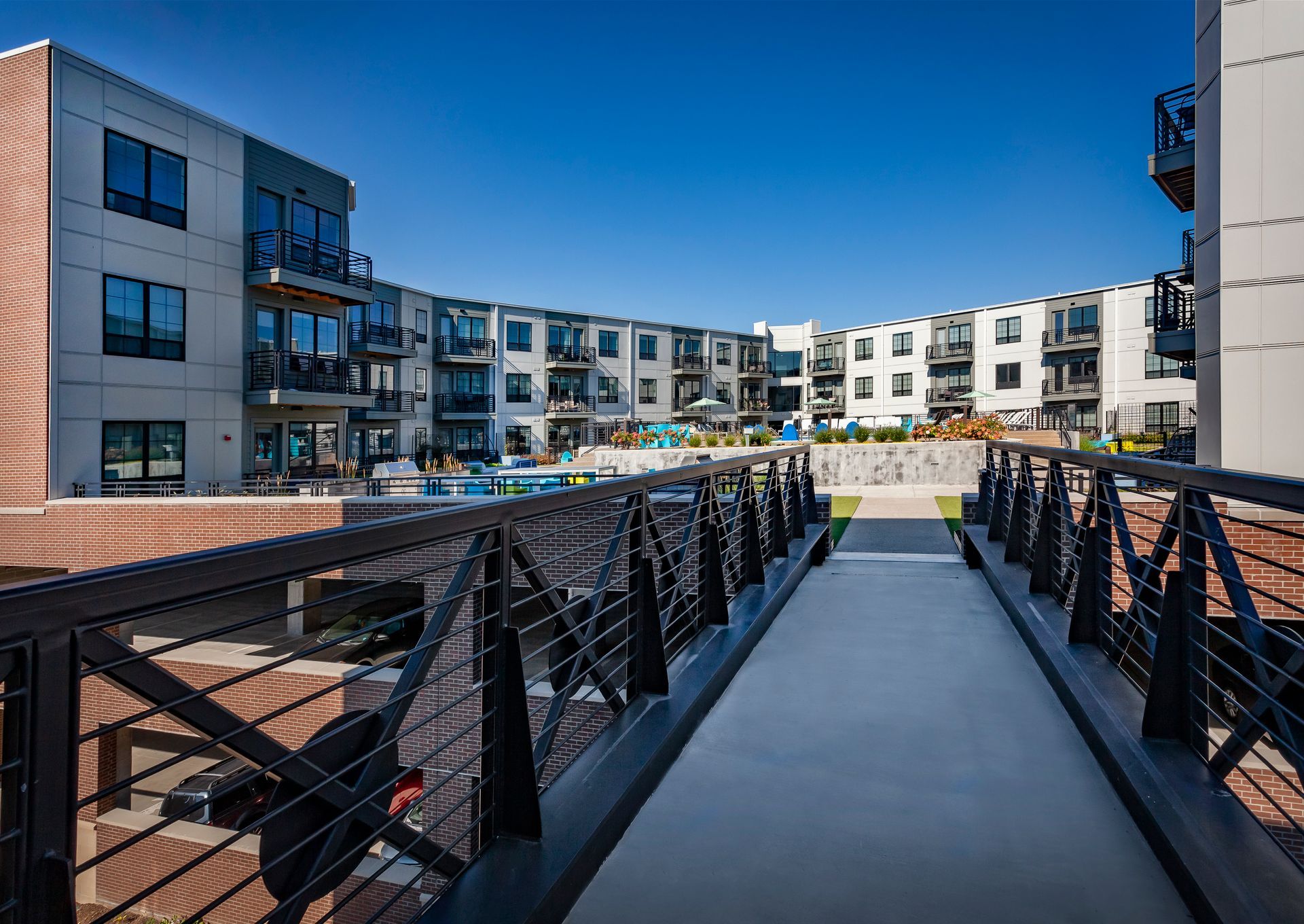 A bridge leading to a large apartment building with a pool in the background at Nickel Plate.