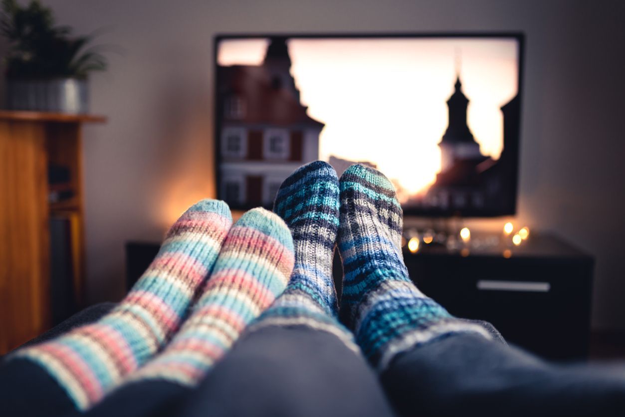 Two pairs of socks are laying on a couch in front of a television.