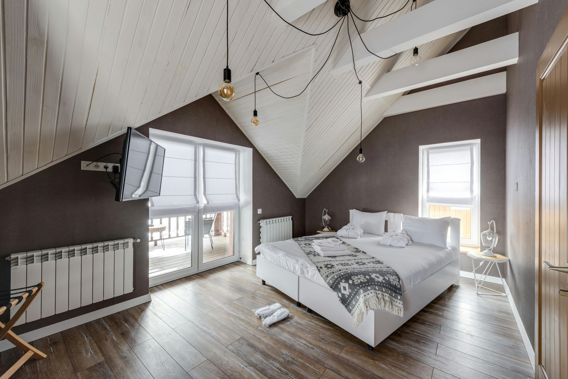 A bedroom with a large bed and a flat screen tv on the wall.