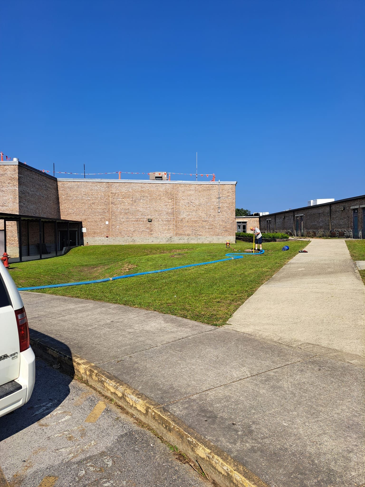 A white van is parked in front of a brick building.