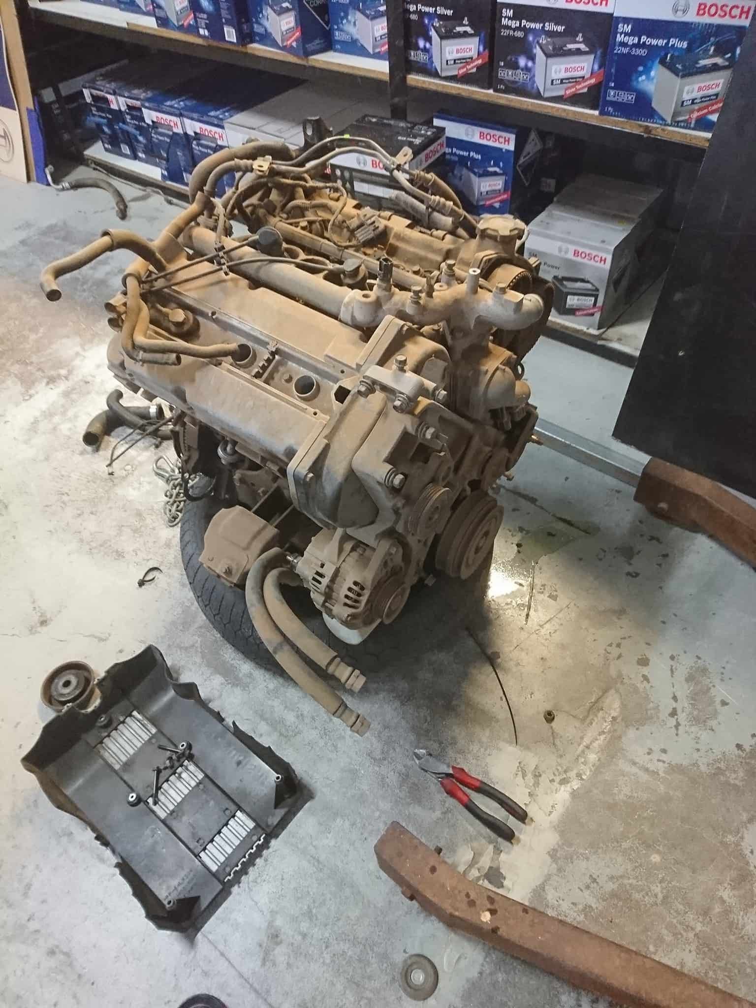 A Dirty Engine Is Sitting On The Floor In A Garage — KC Auto Electrics In Ciccone, NT