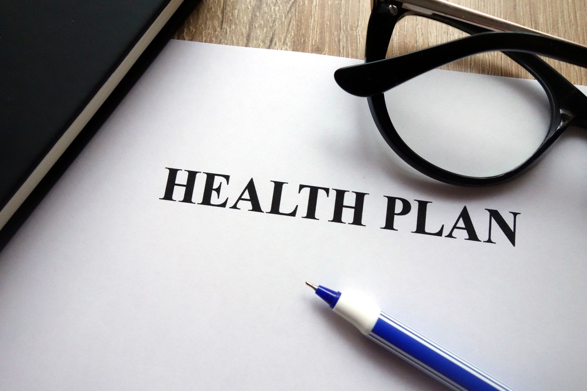 Health plan document with glasses and a blue pen on a desk