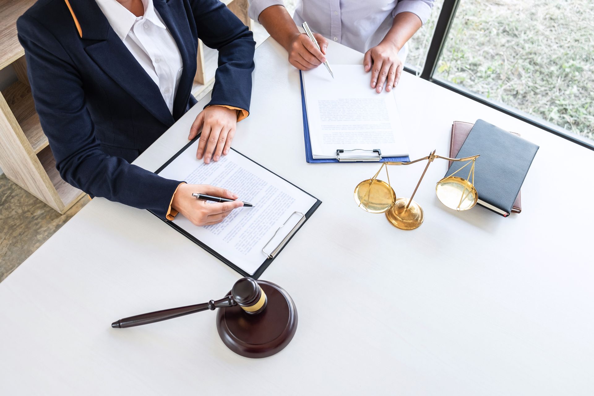 Lawyers reviewing documents at a white conference table with a gavel and scales of justice