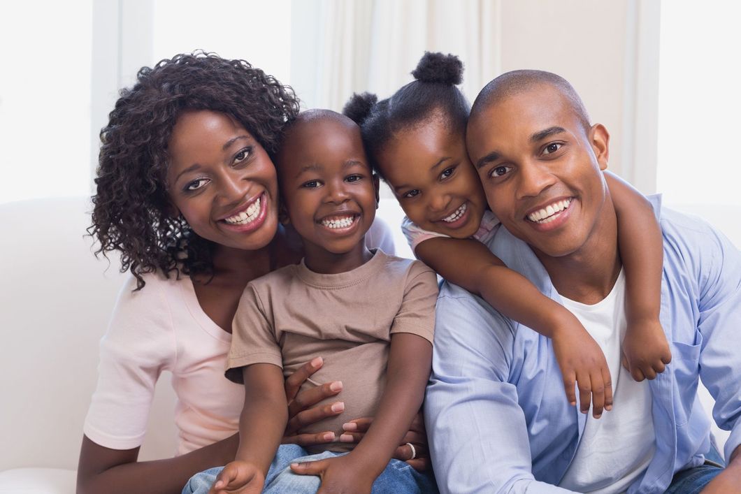 Smiling family sitting together on a couch in a bright living room