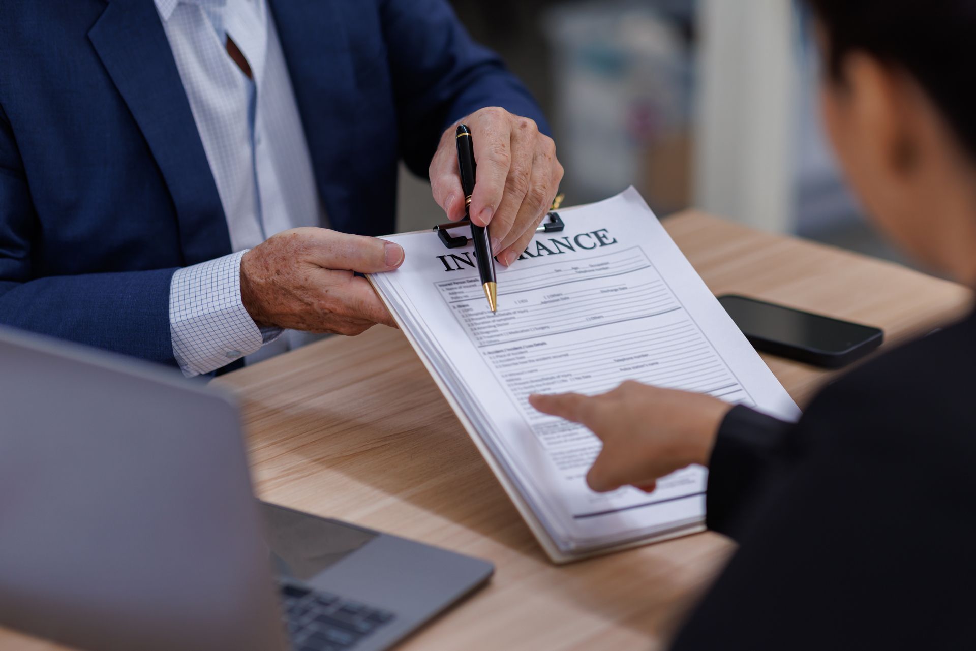 Two people reviewing a document at a desk, one pointing at a page with a pen