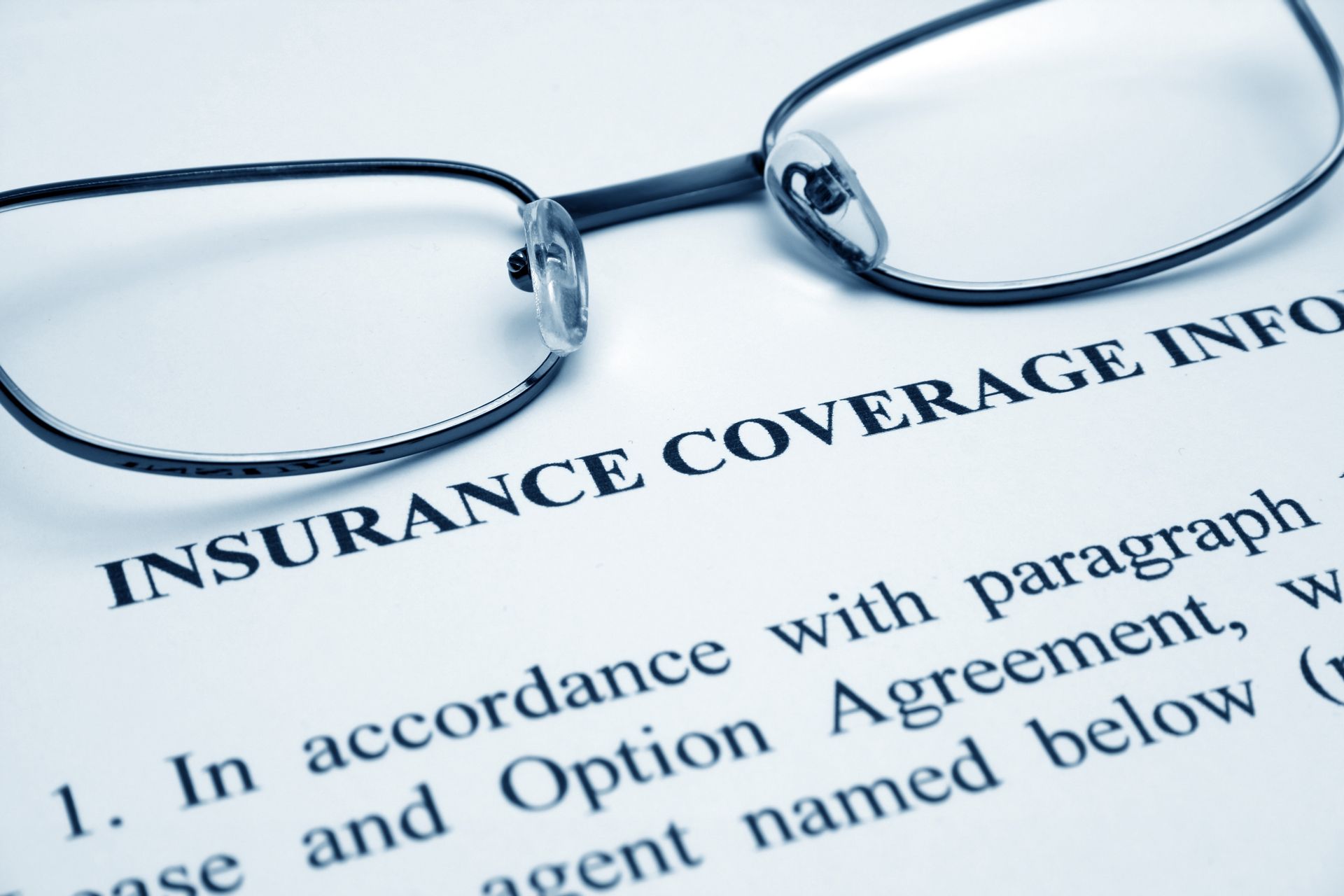 Eyeglasses resting on a printed insurance coverage document with bold heading.