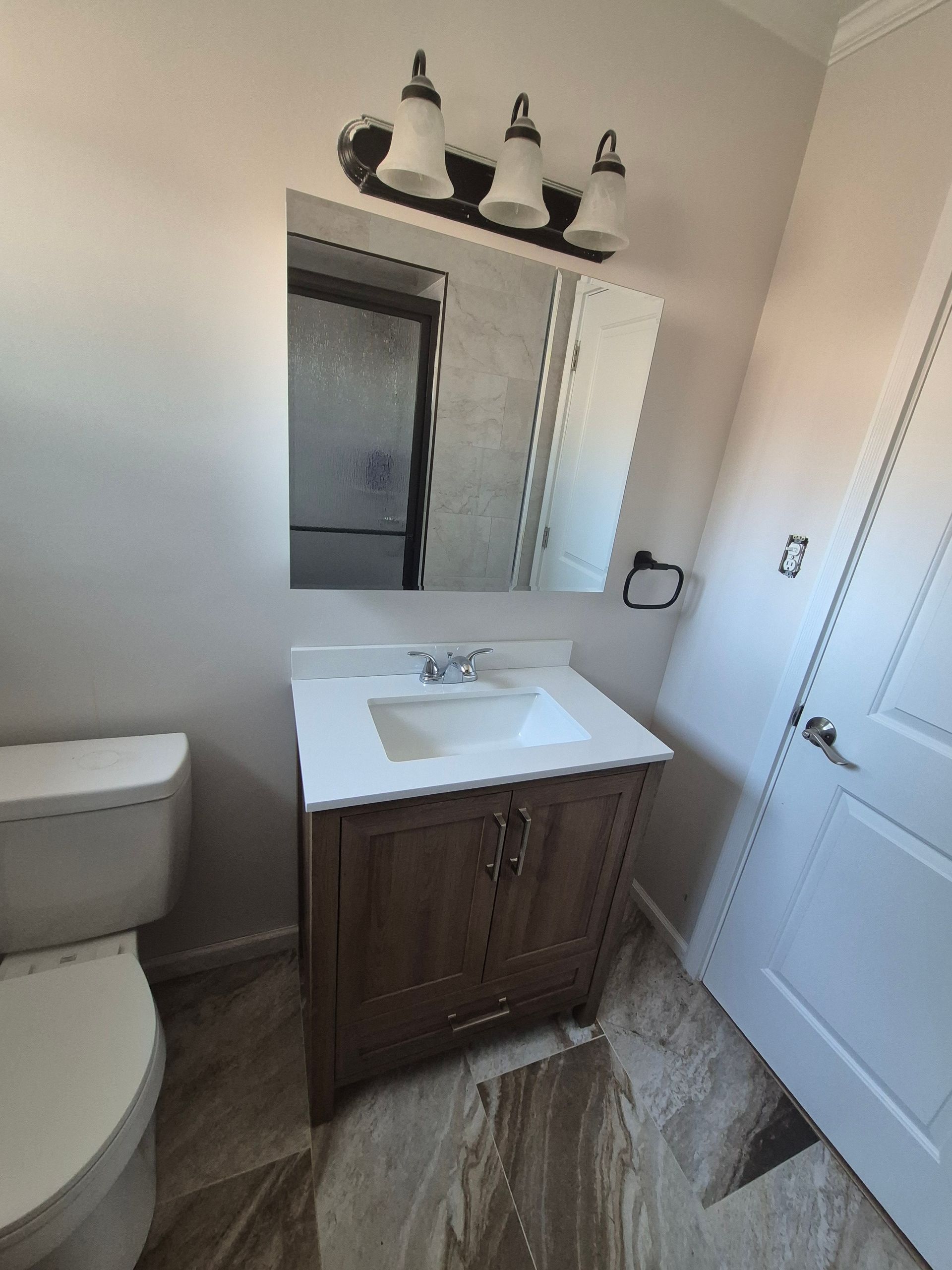 Bathroom with a brown vanity, white sink, square mirror, and a toilet.