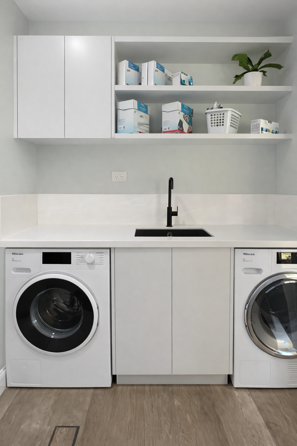 Modern white laundry room with washer, dryer, sink, and storage cabinets on white countertop — Paul Tagget Kitchens In Goonellabah, NSW