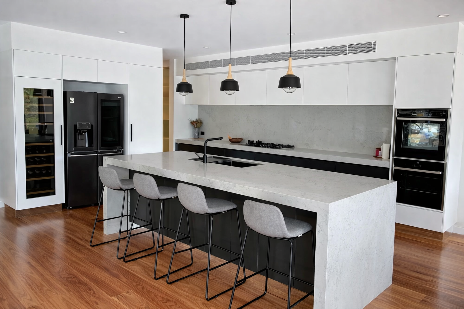 Modern kitchen with a gray island, black appliances, and wooden floor — Paul Tagget Kitchens In Goonellabah, NSW