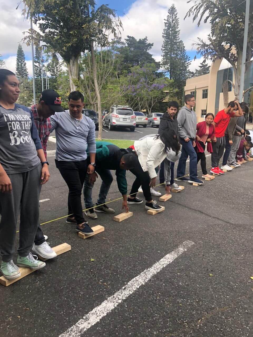 Personas sobre bloques de madera en fila, jugando un juego de equipo en una calle.