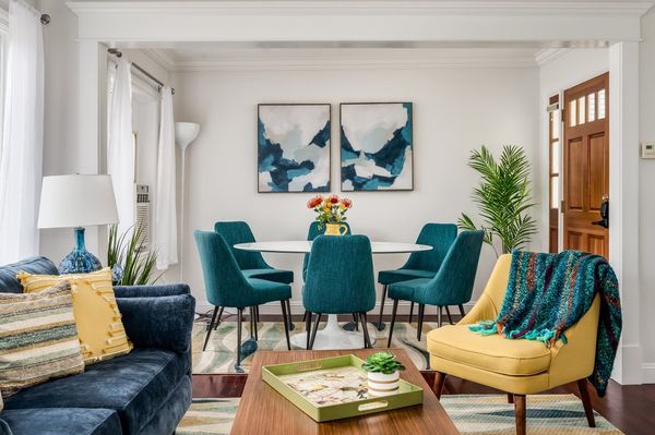 A living room featuring two yellow chairs, a blue couch, a wooden coffee table, and a staircase leading to an upper floor.