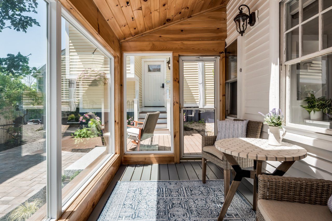 Sunroom with wood ceiling, large windows looking outdoors, and a small round bistro table with two chairs.