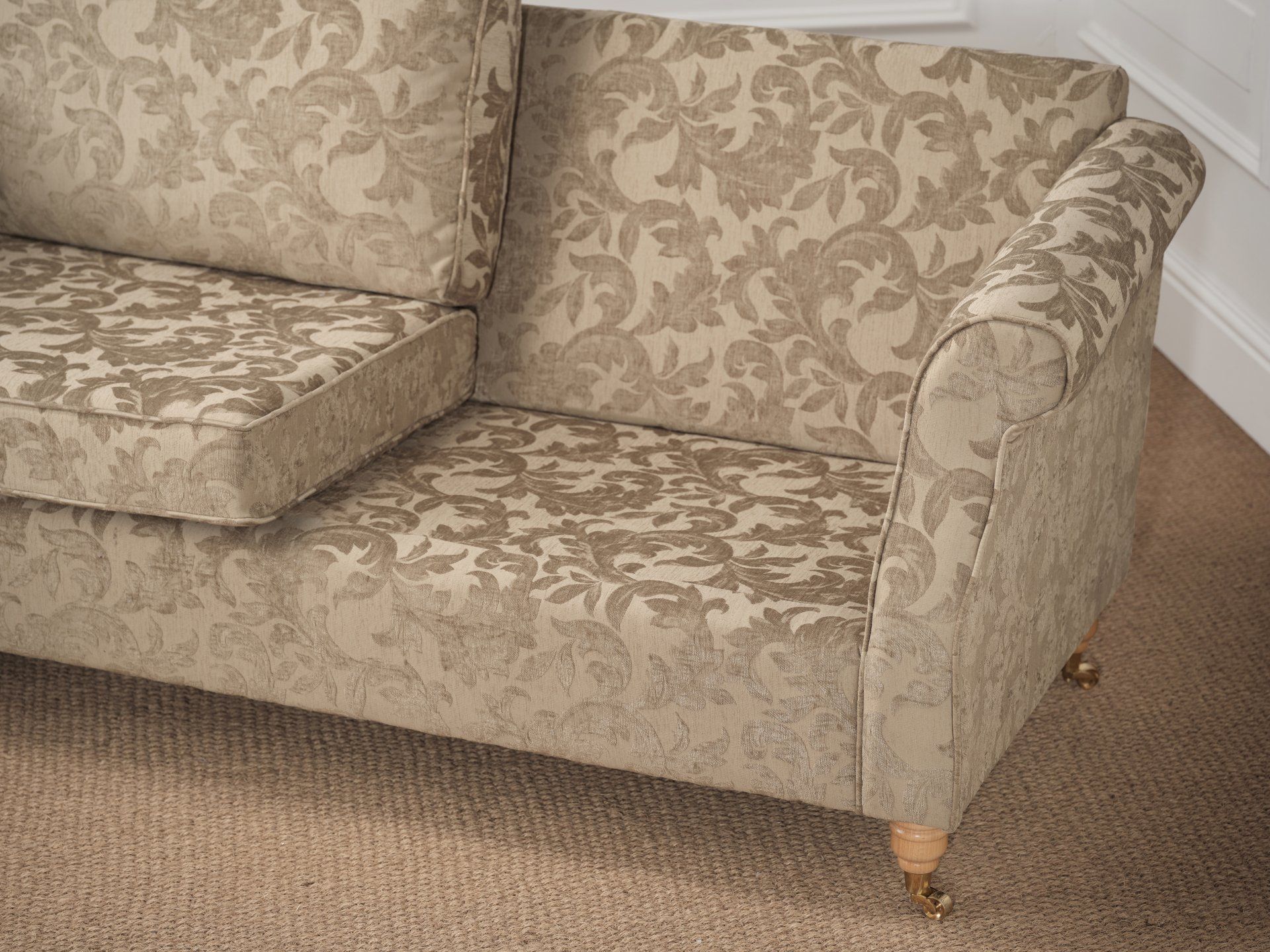 A couch with a pattern on it is sitting on a carpet.
