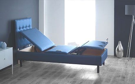 A blue adjustable bed is sitting in a bedroom by Churchill Chairs