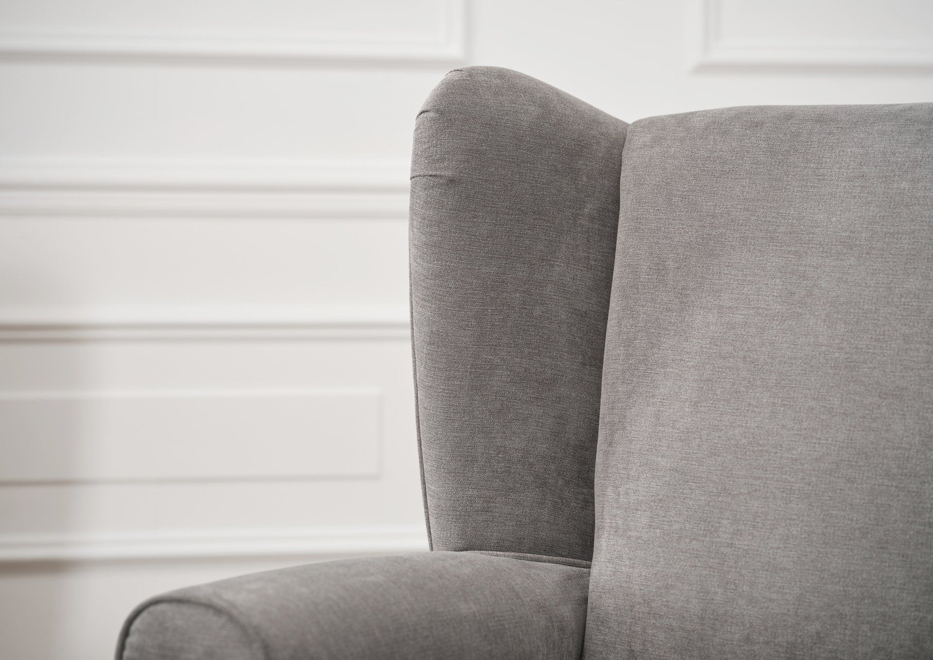 A close up of a grey chair in front of a white wall.
