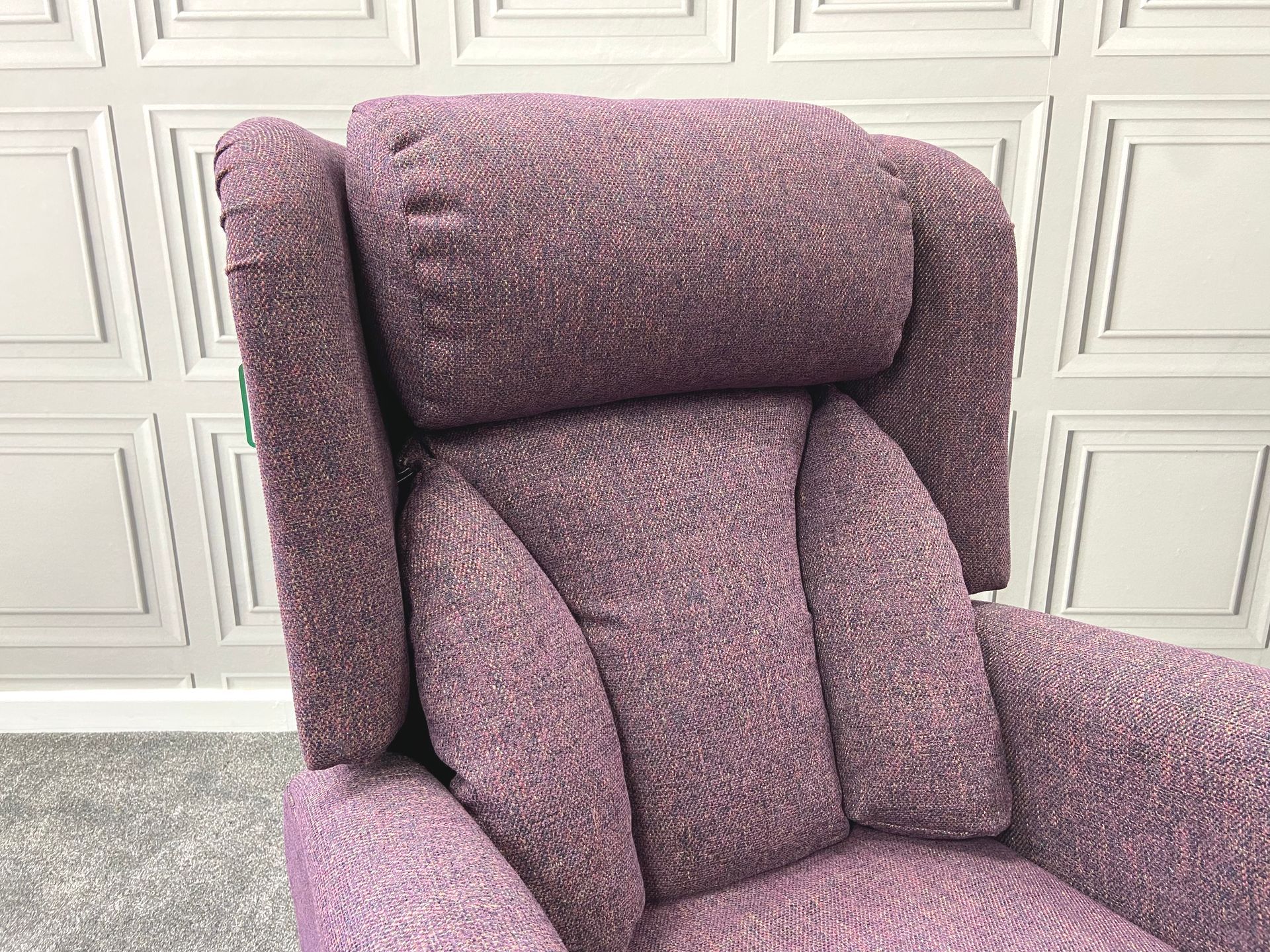A purple recliner is sitting in front of a white wall.