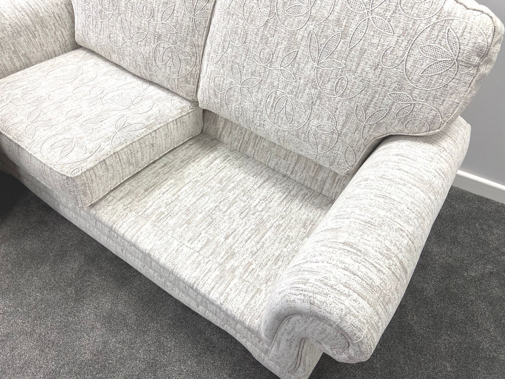 A white couch is sitting on a carpet in a room.