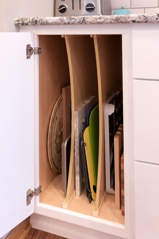 Cabinet with dividers organizing baking sheets and trays in a kitchen.