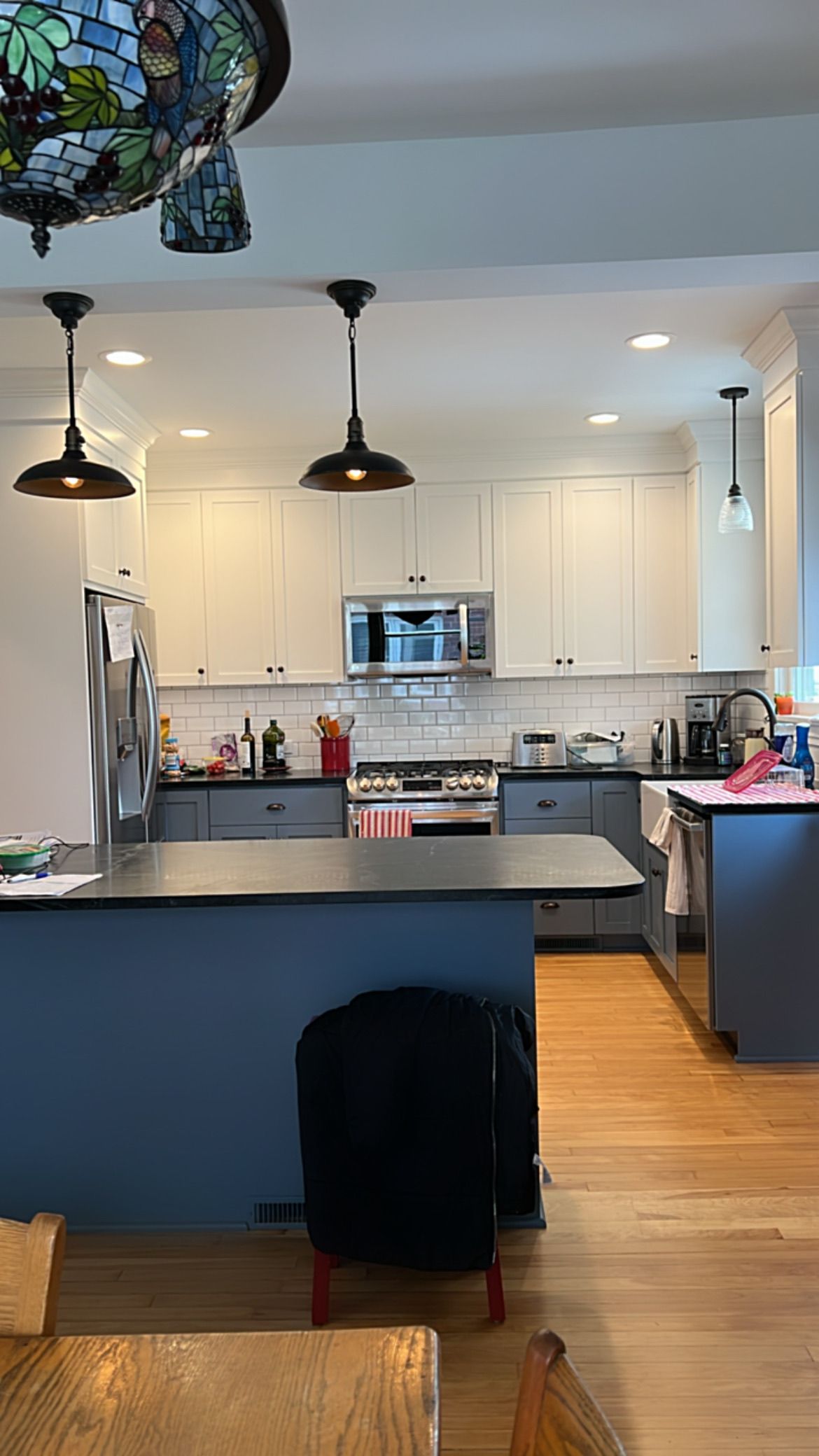 Kitchen with blue island, white cabinets, and pendant lights.