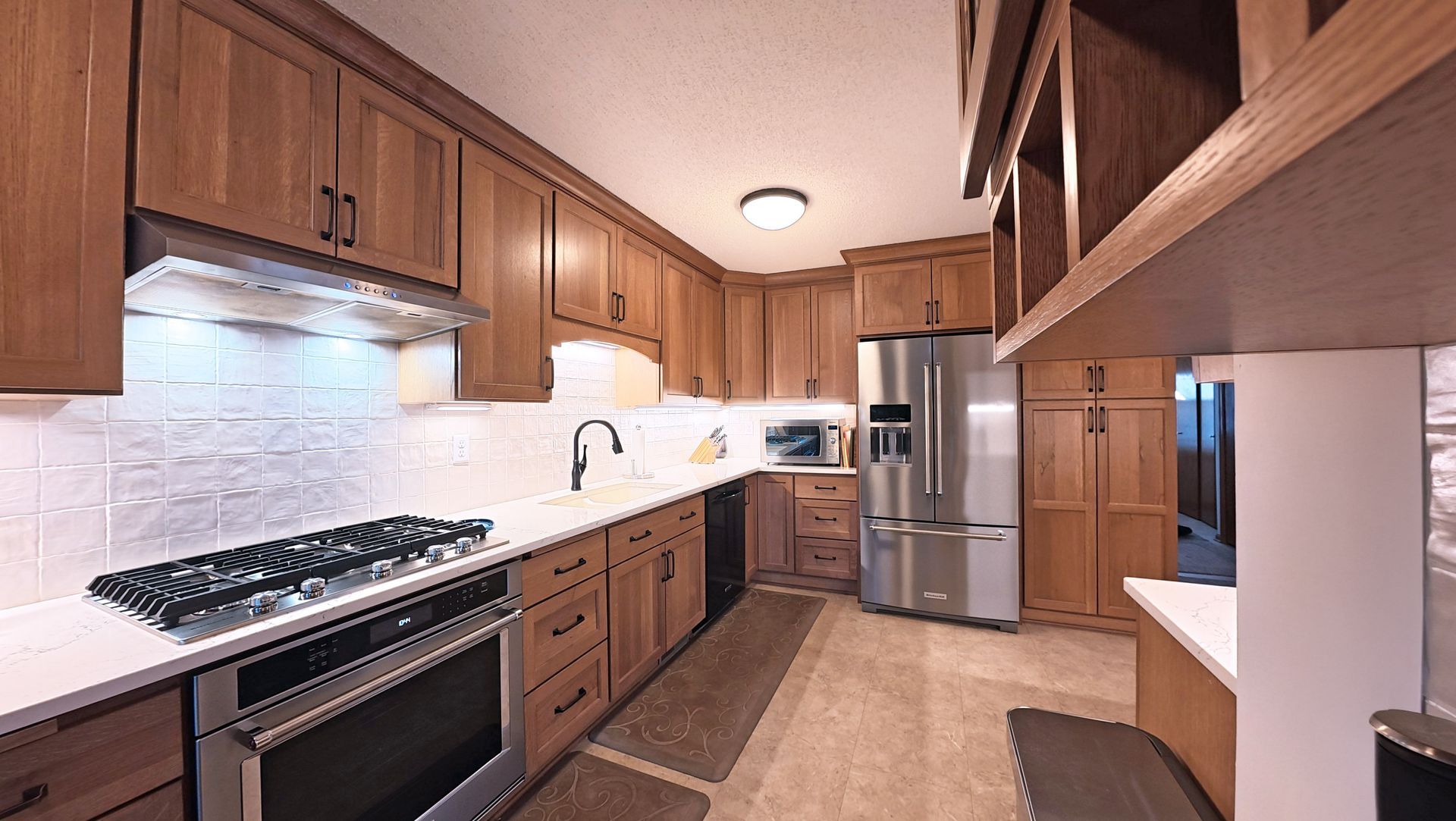 Kitchen with wooden cabinets, stainless steel appliances, and white countertops.