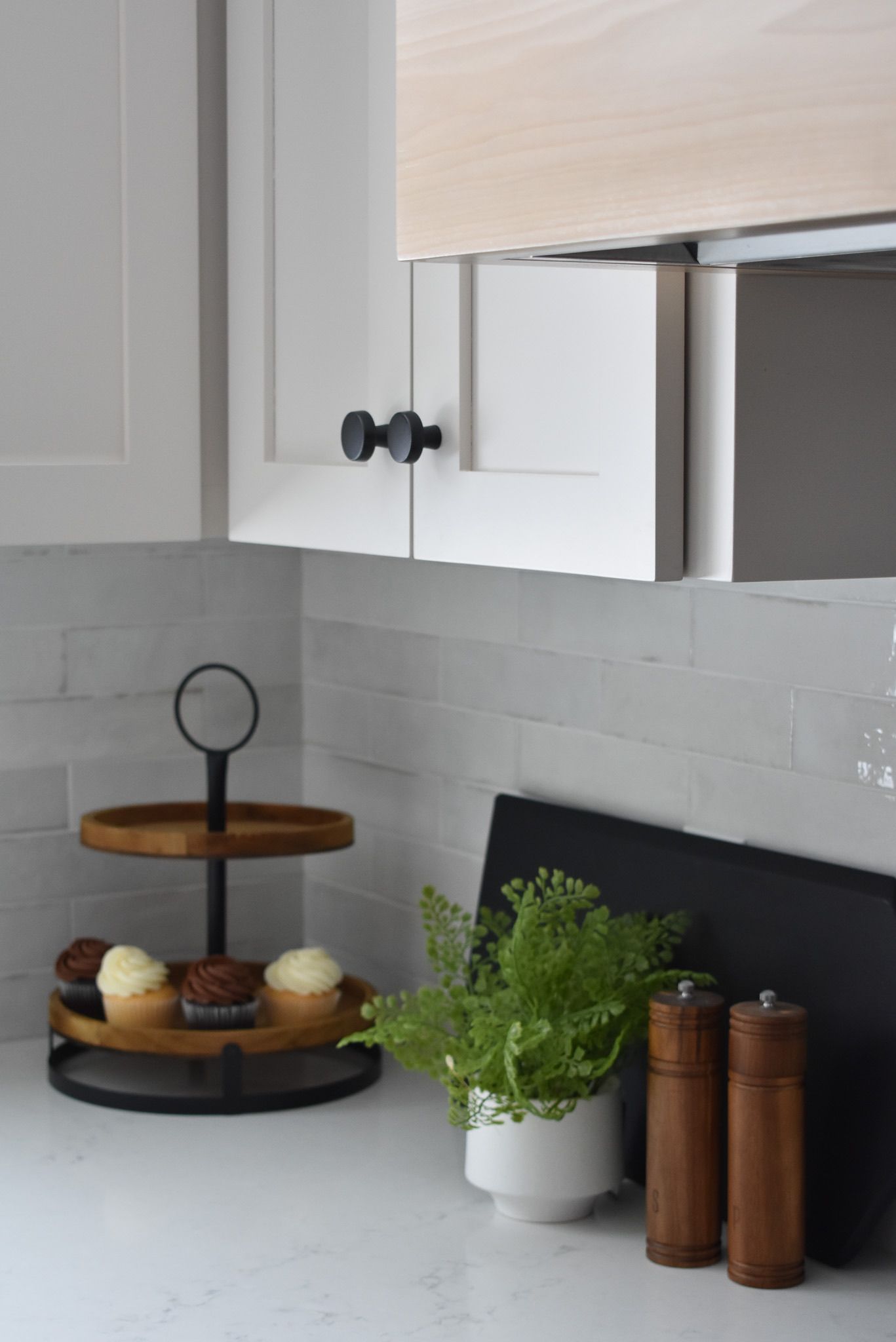 Kitchen counter with tiered tray of treats, plant, and salt and pepper shakers.