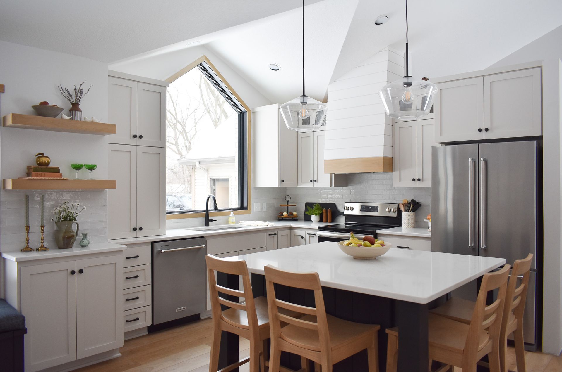 Modern white kitchen with island, stainless steel appliances, and wood accents.