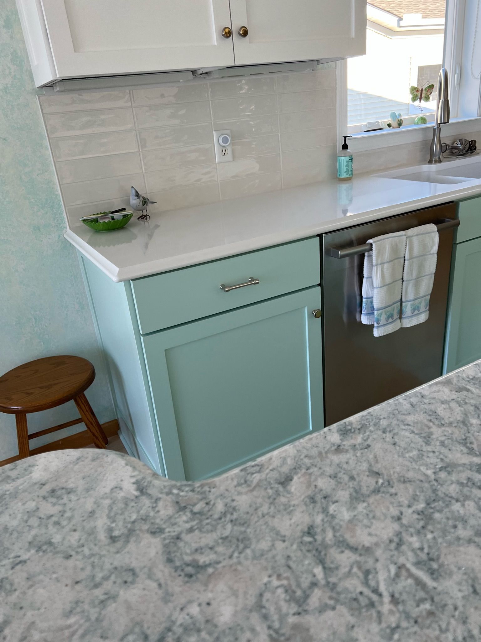 Kitchen with light blue cabinets, white countertops, and stainless steel dishwasher.