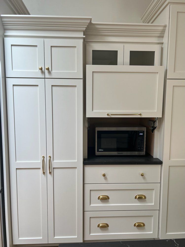 White kitchen cabinets with a microwave, drawers, and gold hardware.