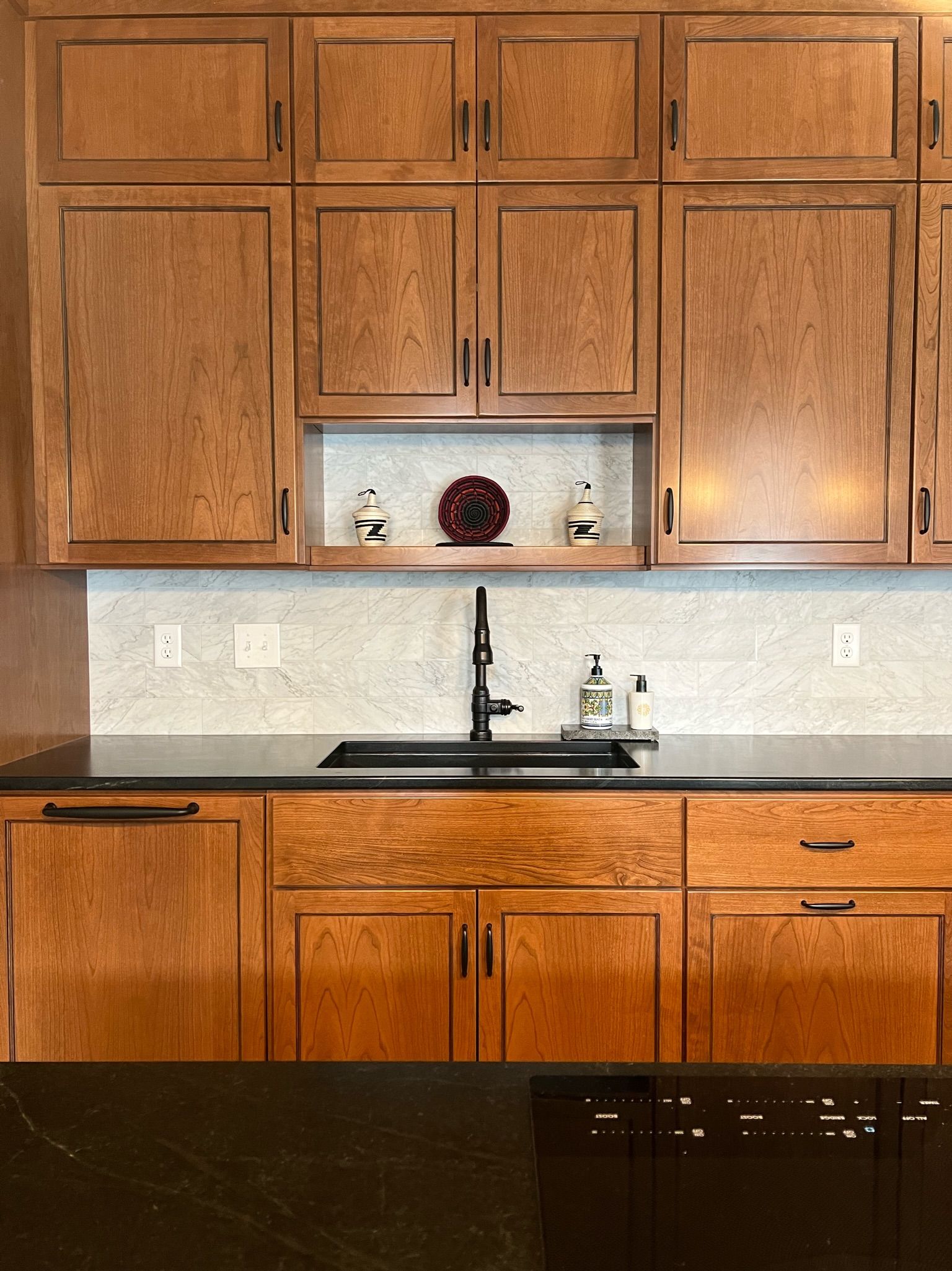 Kitchen with wood cabinets, black countertops, and a black sink.