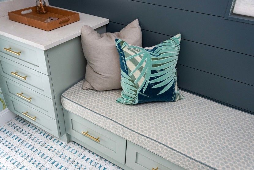 Built-in bench with drawers, light blue paint, white countertop, and patterned pillows.