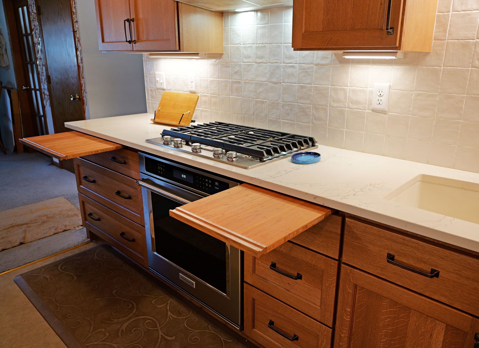 Kitchen with light wood cabinets, countertop, stove, oven, and pull-out shelves.