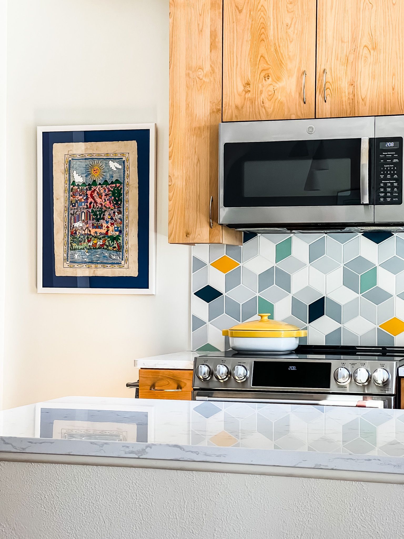 Kitchen with colorful geometric backsplash, microwave, wooden cabinets, and framed art.
