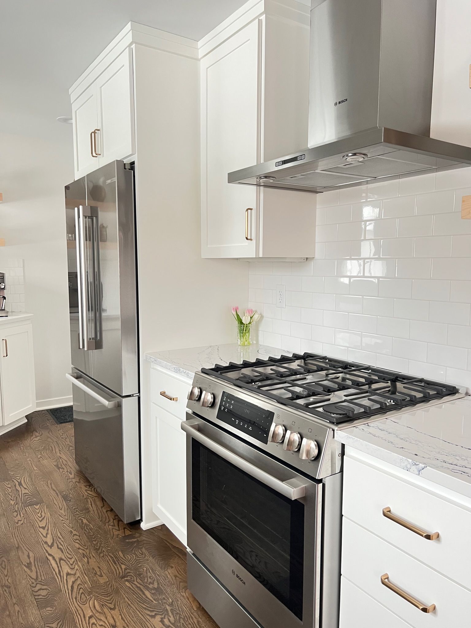 White kitchen with stainless steel appliances, cabinets, and a gas range.