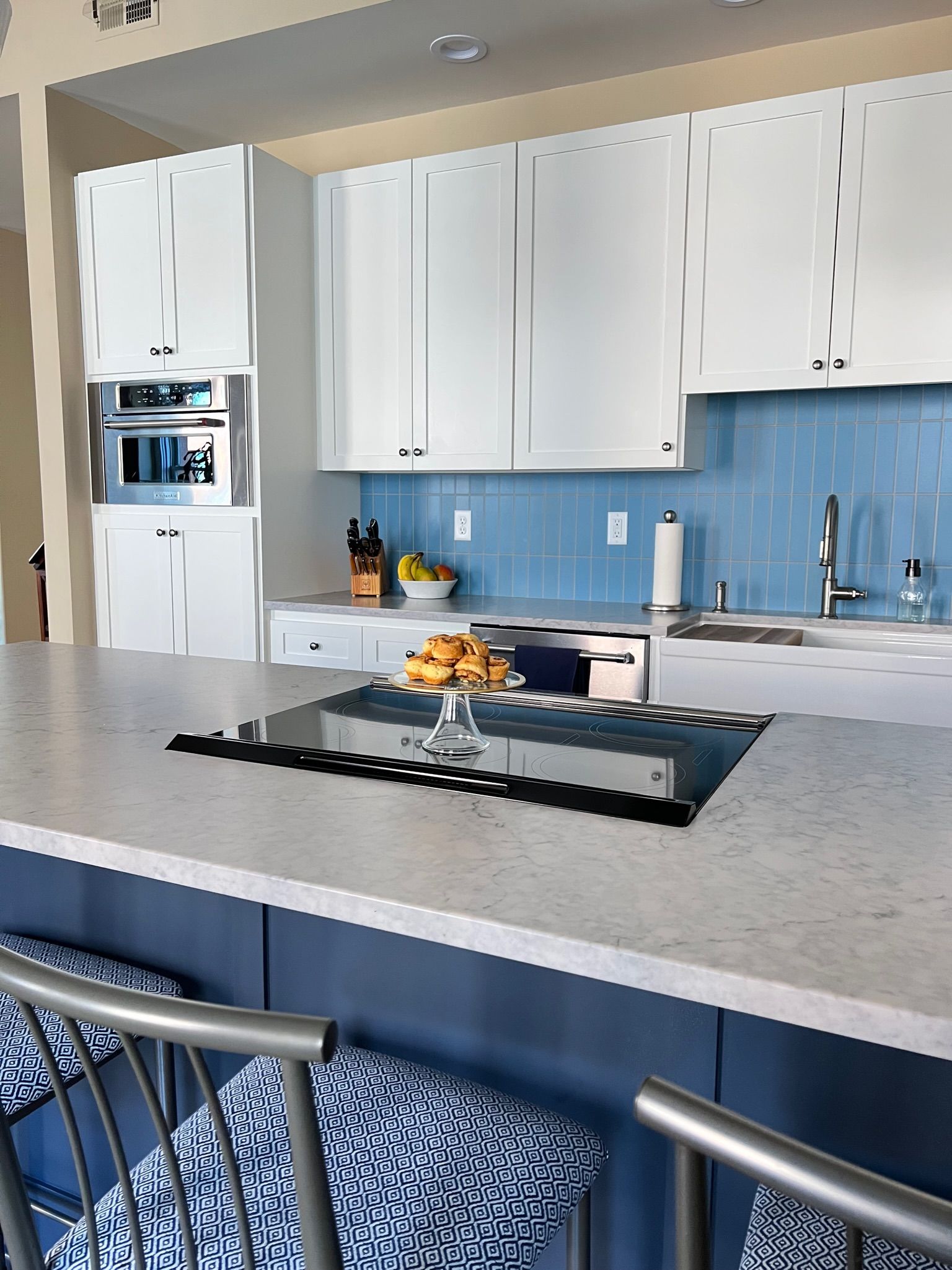 Modern kitchen with white upper cabinets, blue backsplash, and blue island.