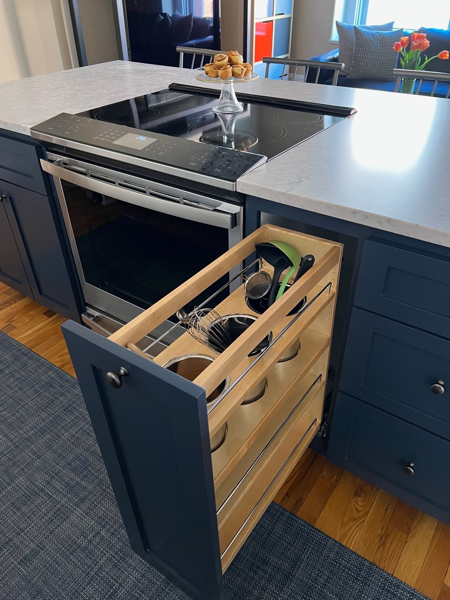Kitchen island with a pull-out spice rack and oven, navy blue cabinets, and white countertop.