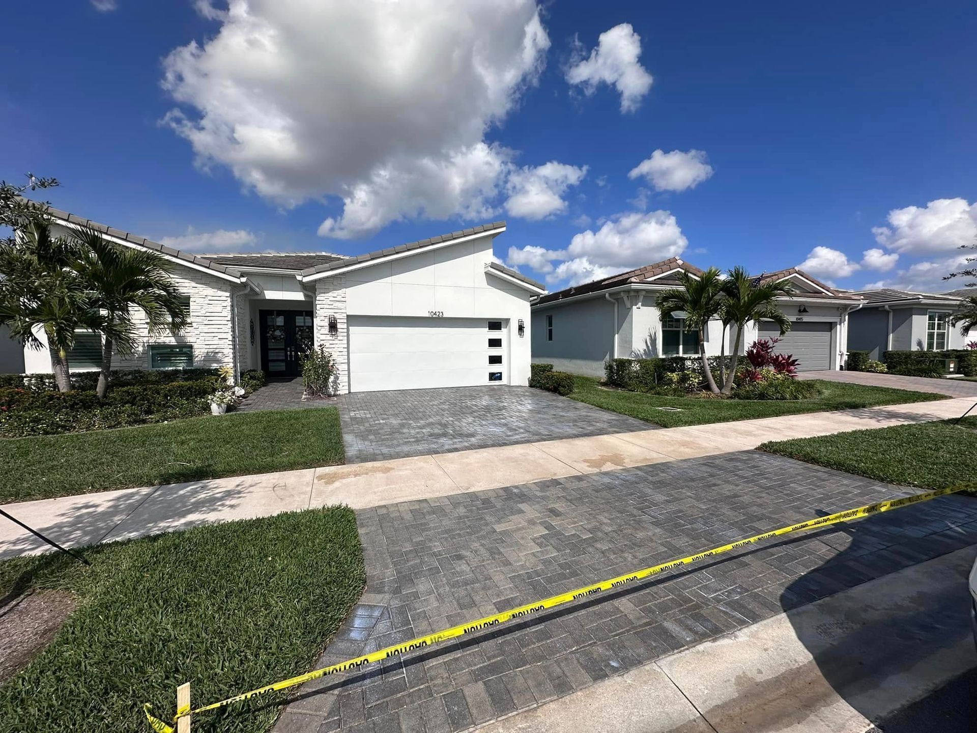 Row of modern houses with decorative gray driveways under a partly cloudy sky.