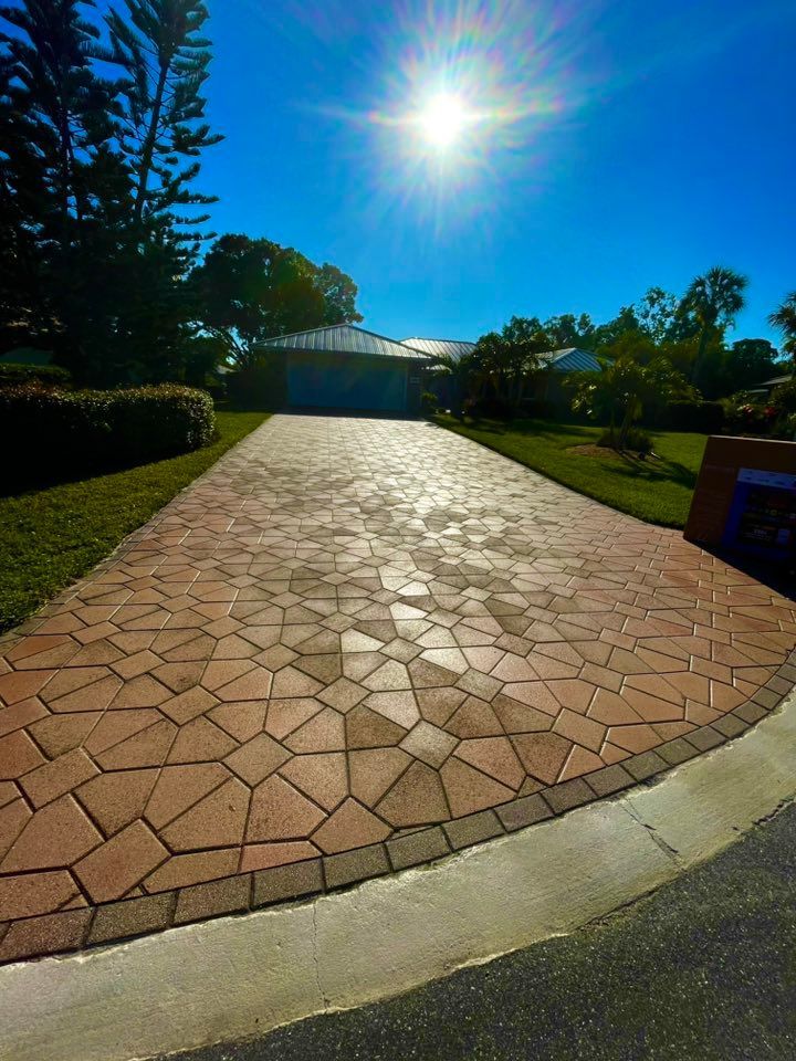 Brick driveway leading to a house under a bright sun.