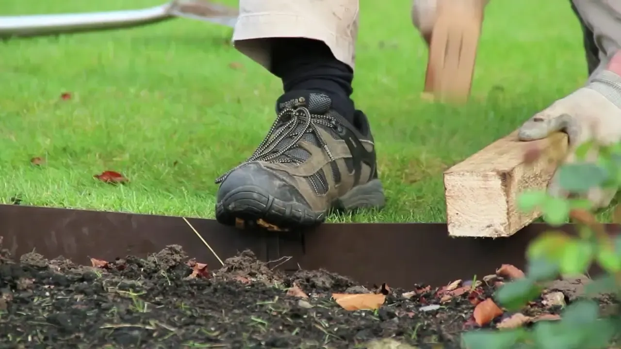 a rusty metal edging is sitting on top of a pile of gravel .