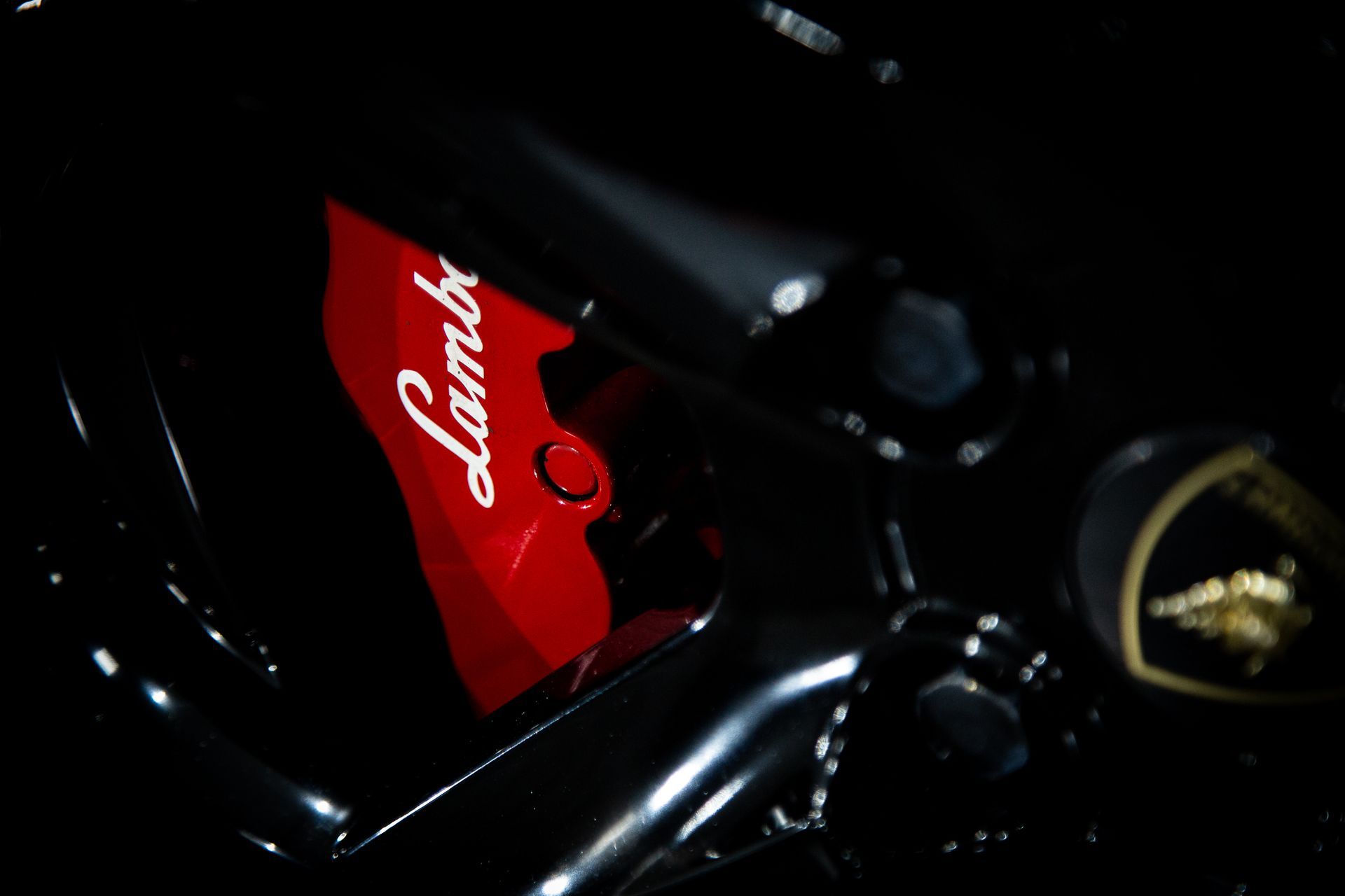 Close-up of a red Ferrari badge on a glossy black car body