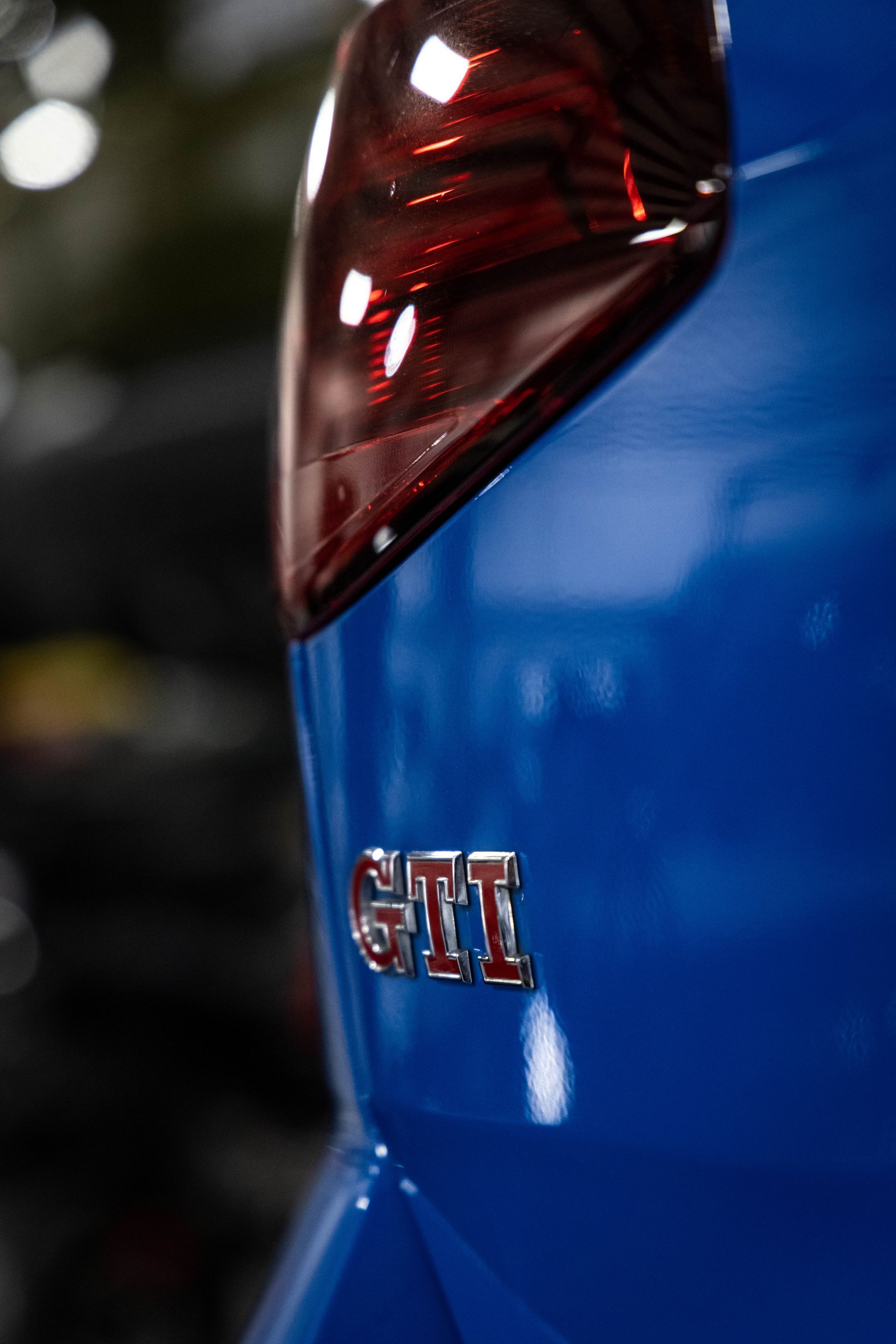 Close-up of a blue car’s rear with red taillight and GTI badge