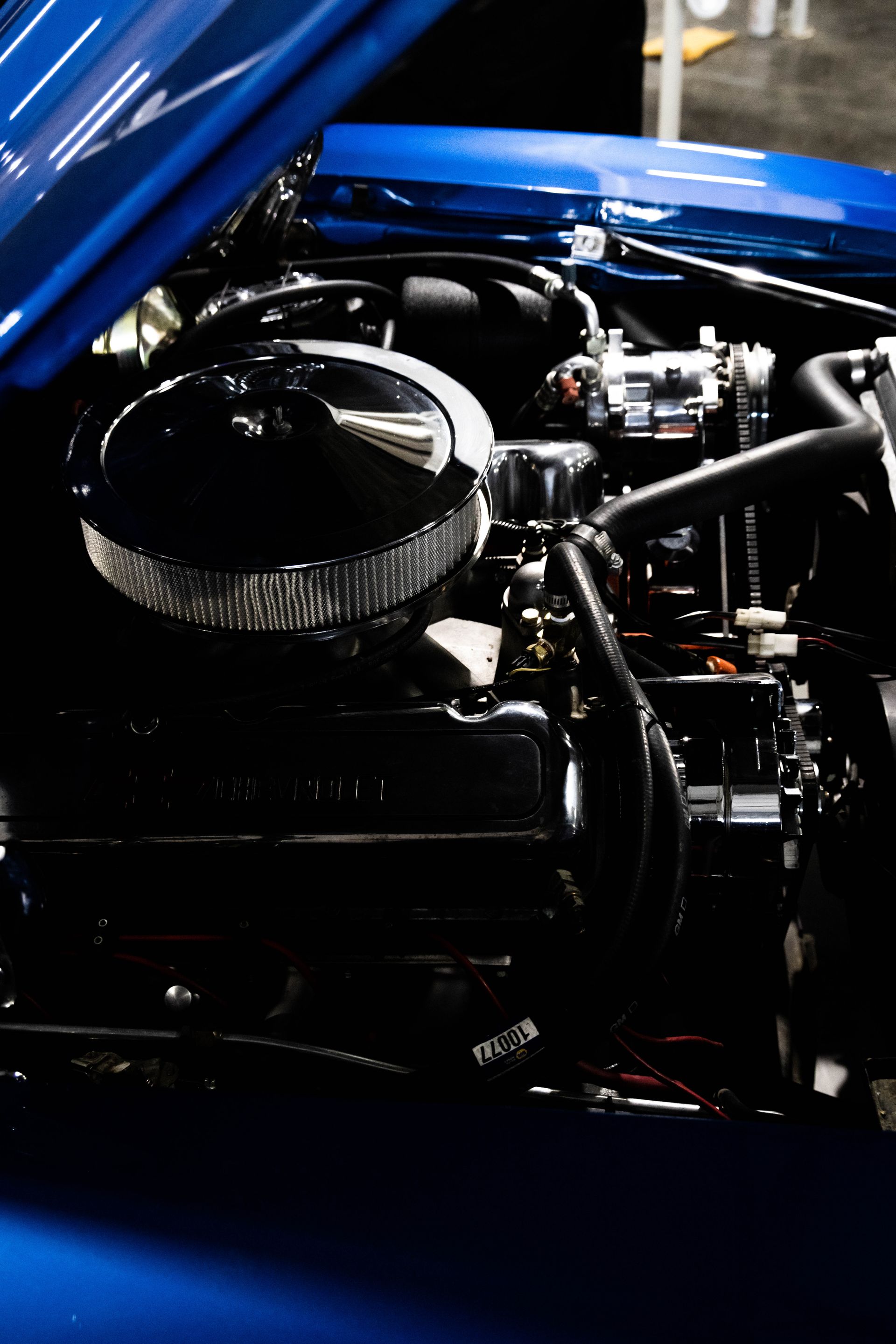 Close-up of a blue car’s engine bay with a large air filter and polished components