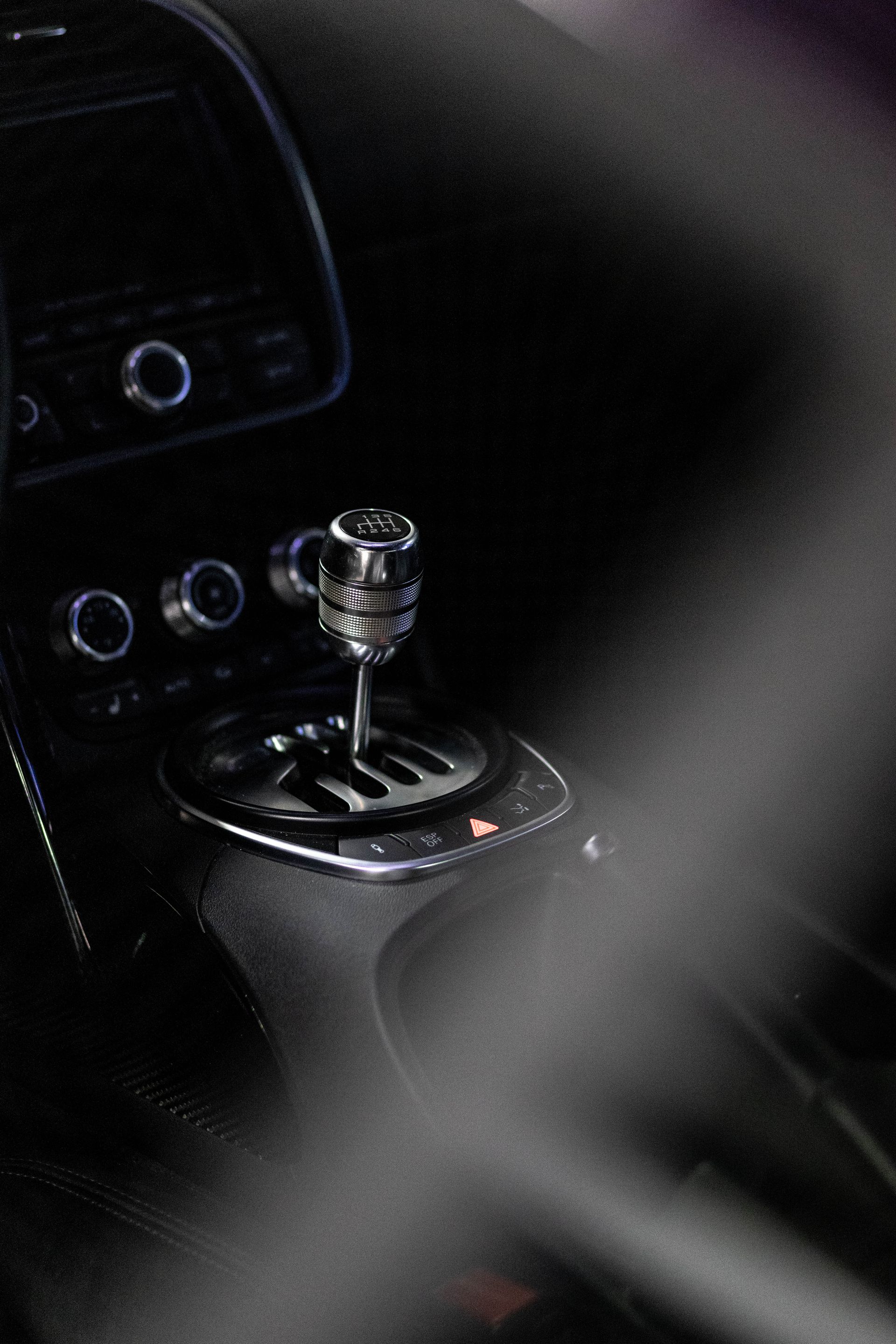 Close-up of a car’s gear shift lever and center console controls in low light