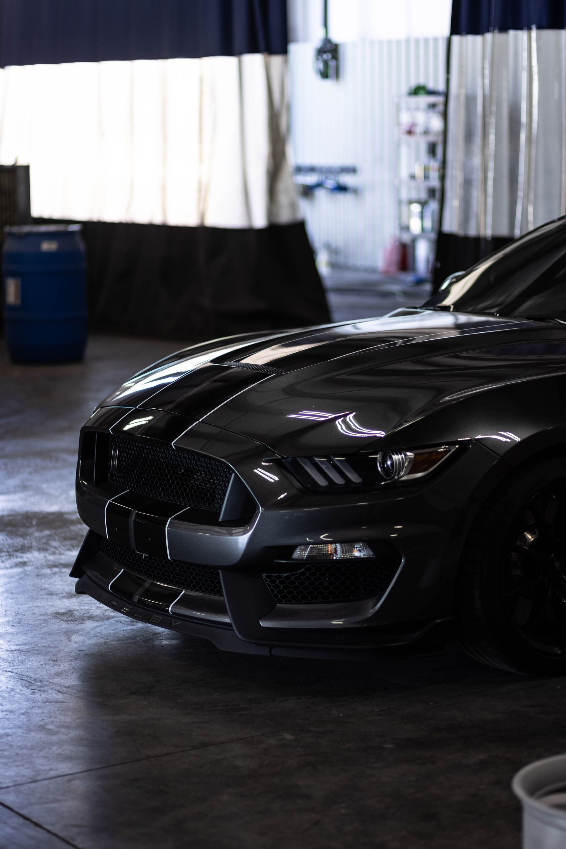 Black sports car parked indoors in a dim garage or showroom, front view visible.