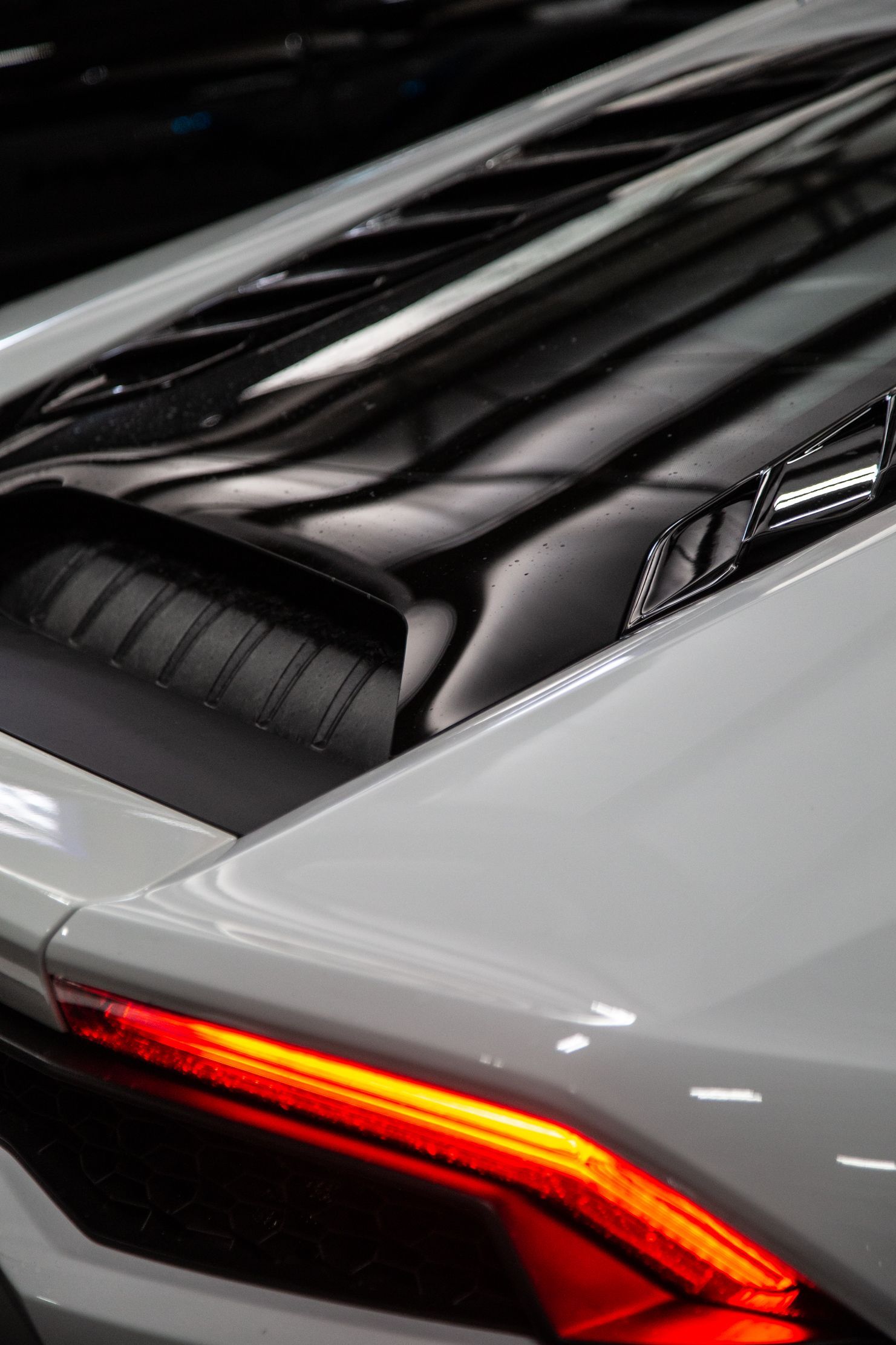 Close-up of a white sports car’s rear with a red taillight and black glass roof stripe