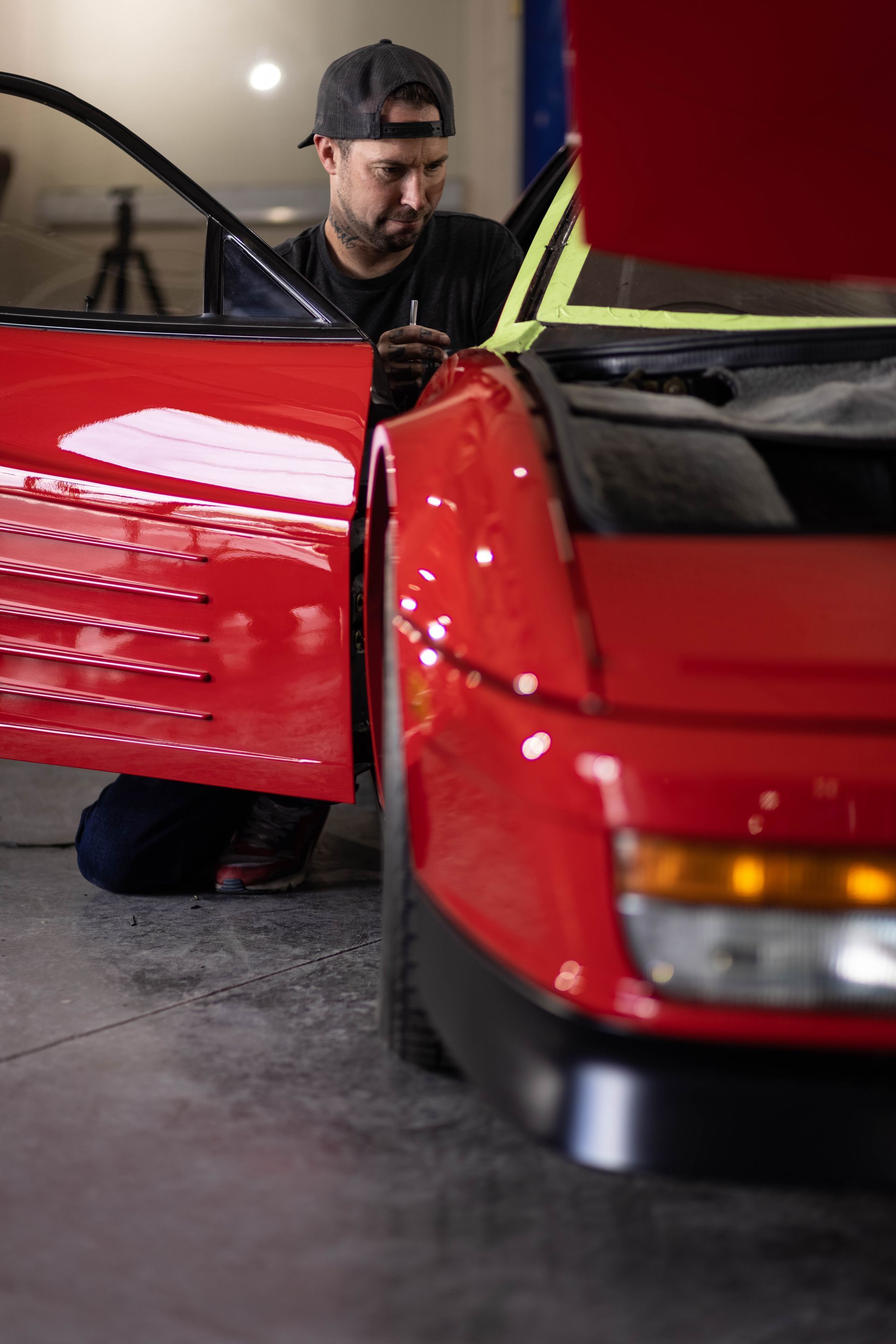 Mechanic working on a red sports car with the driver’s door open in a garage